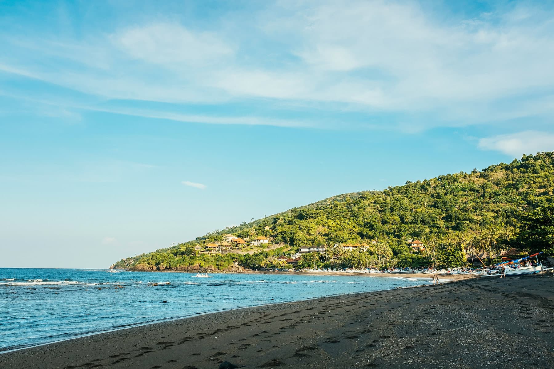 Groene landtong die de zee in steekt bij Amed, met helder turquoise water en een donker kiezelstrand