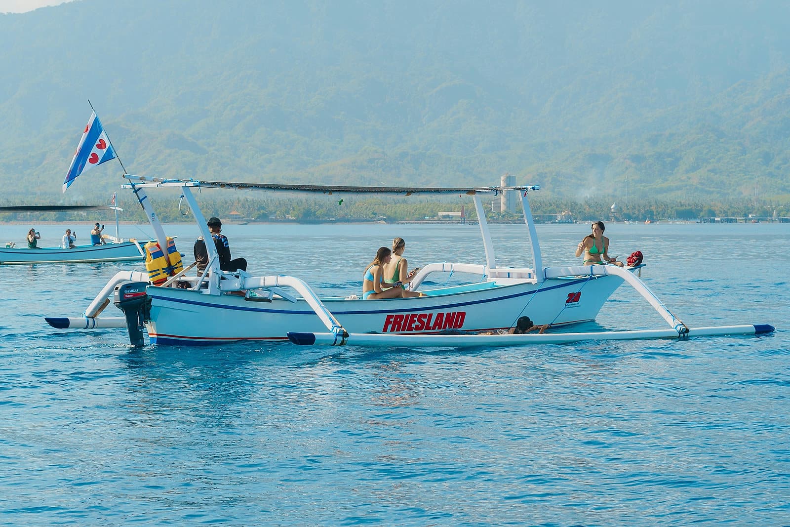 Traditionele Balinese boot met snorkelaars aan boord op helder blauw water voor de kust