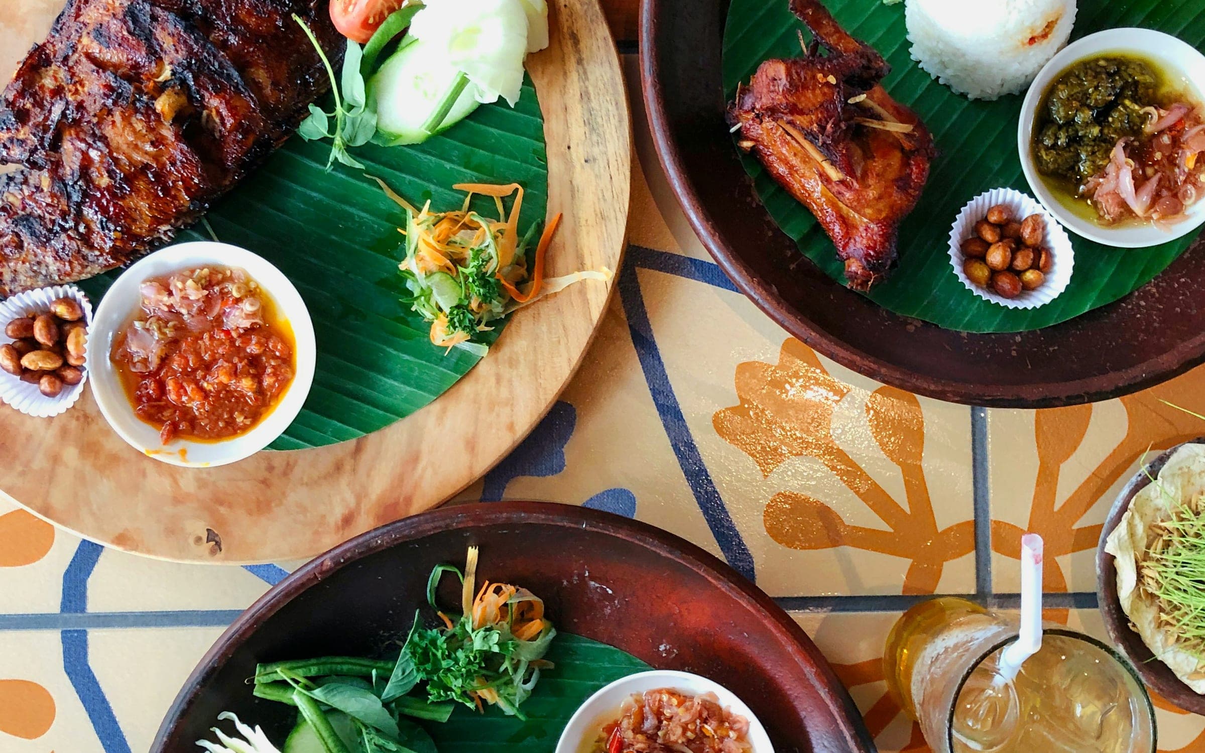 Verschillende Balinese schotels met rijst, sambal en pinda’s op houten borden