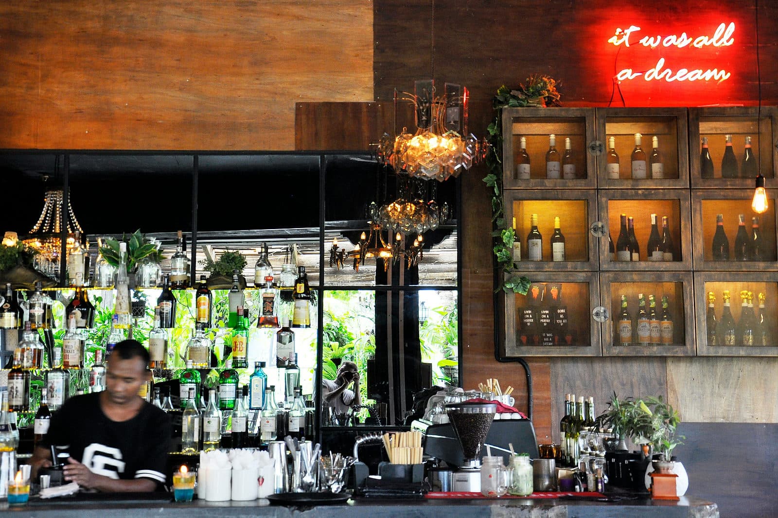 Barman achter een bar met flessen en planten in een zaak in Canggu op Bali