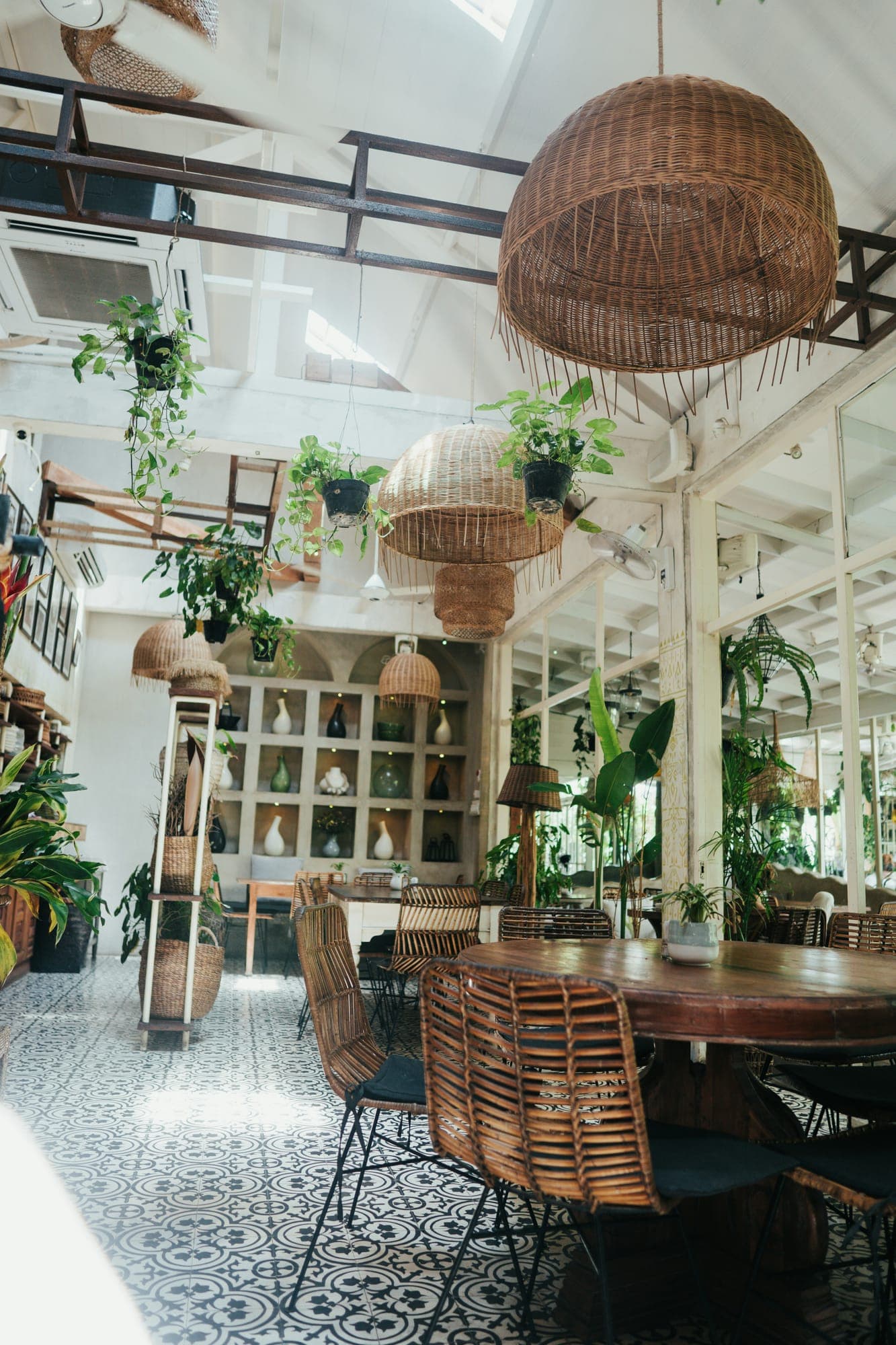 Licht café-interieur met rotan lampen, planten en houten meubels in Canggu