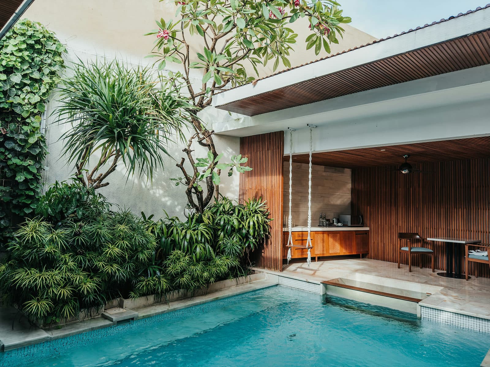 Zwembad naast een moderne villa met houten gevel en planten op Bali