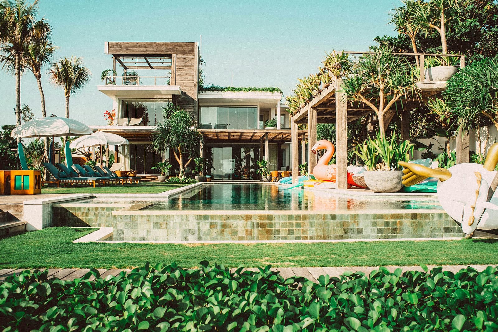 Moderne villa met een groot zwembad en ligbedden tussen tropisch groen op Bali