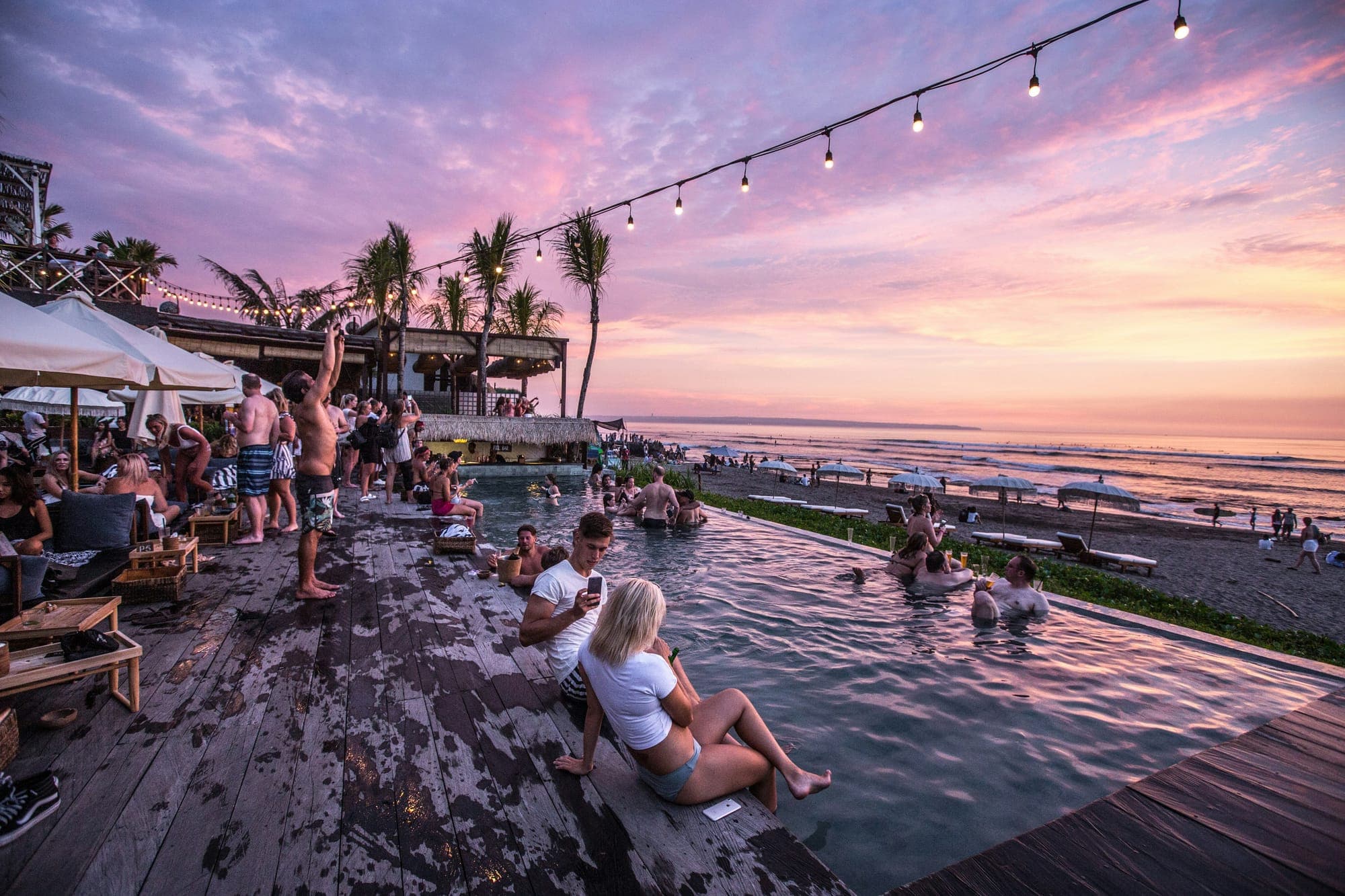 Zonsondergang boven het zwarte strand en de golven bij Canggu op Bali