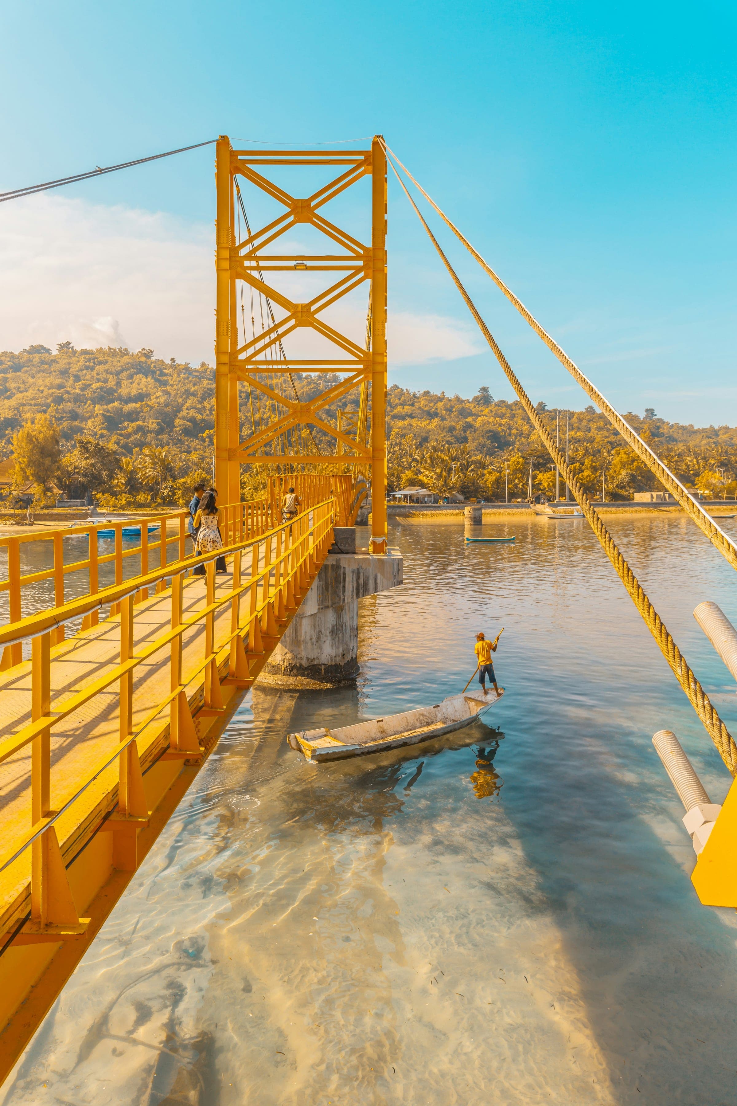 De smalle gele hangbrug tussen Nusa Lembongan en Nusa Ceningan met een visser in het kanaal eronder