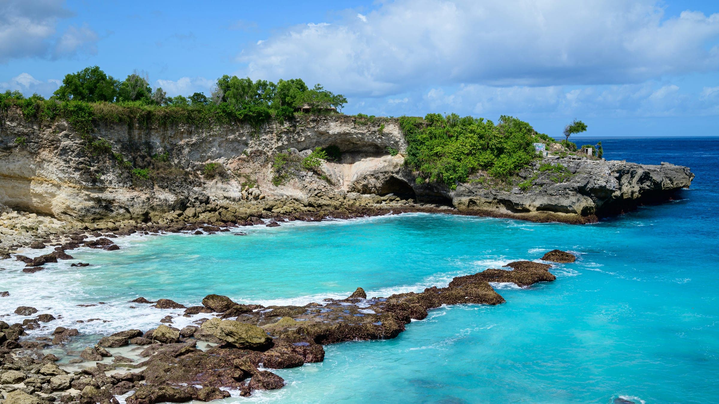 Felblauw water tussen de kalkrotsen aan de kust van Nusa Ceningan