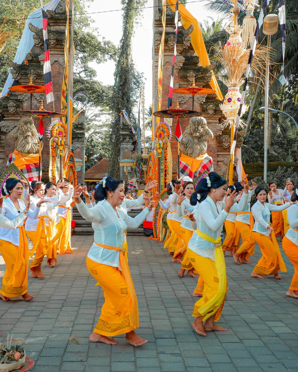 Balinese vrouwen in traditionele kleding dansen tijdens een ceremonie bij een tempel