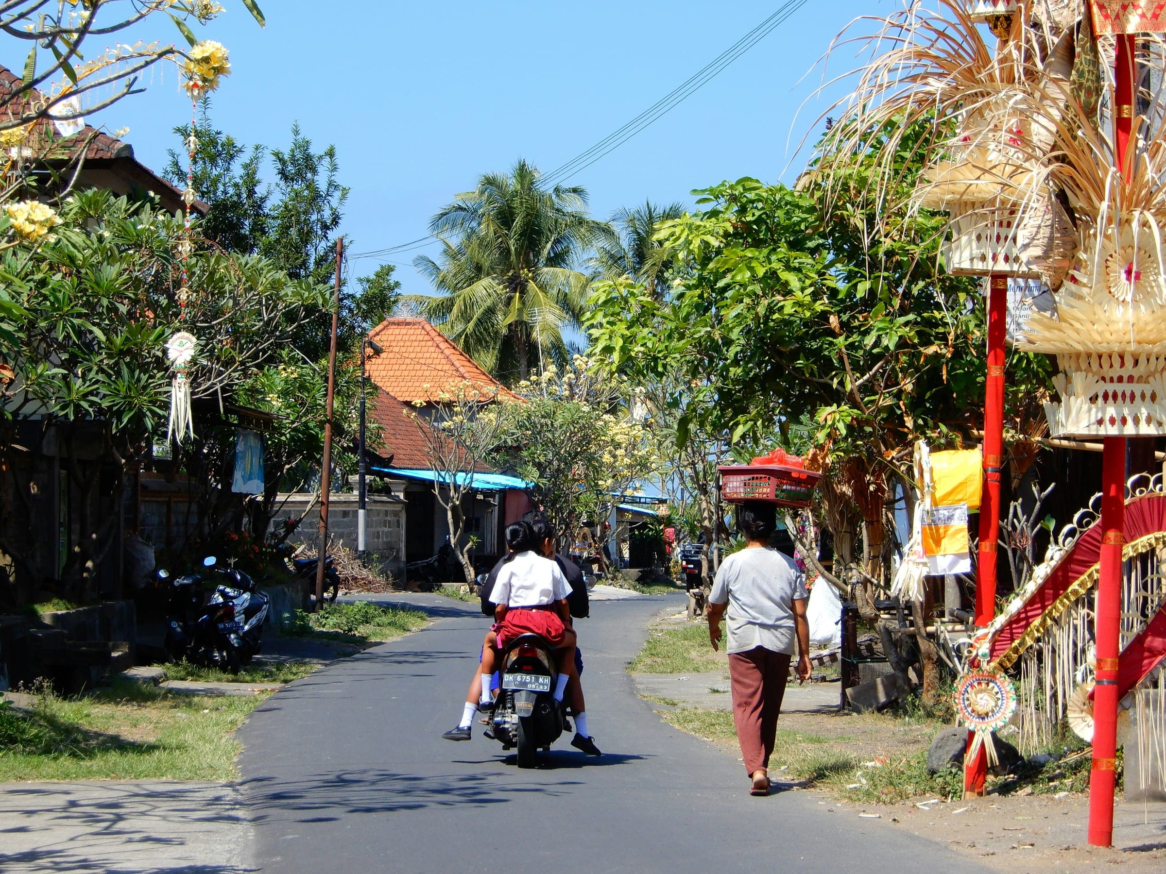 Een Balinese dorpsstraat met scooters, warungs en tempelpoorten