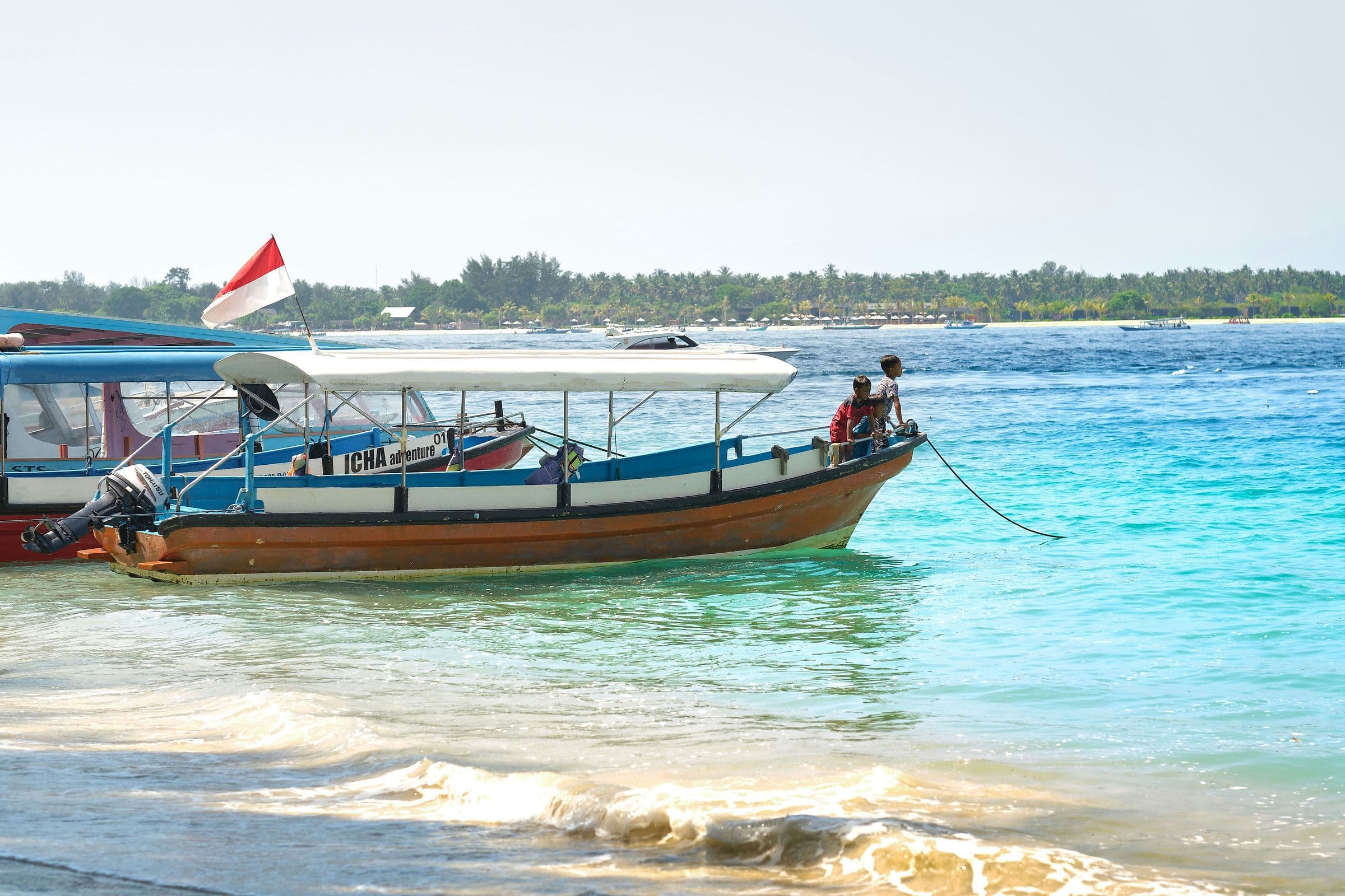 Een boot met Indonesische vlag ligt aan de waterlijn van een Gili-eiland