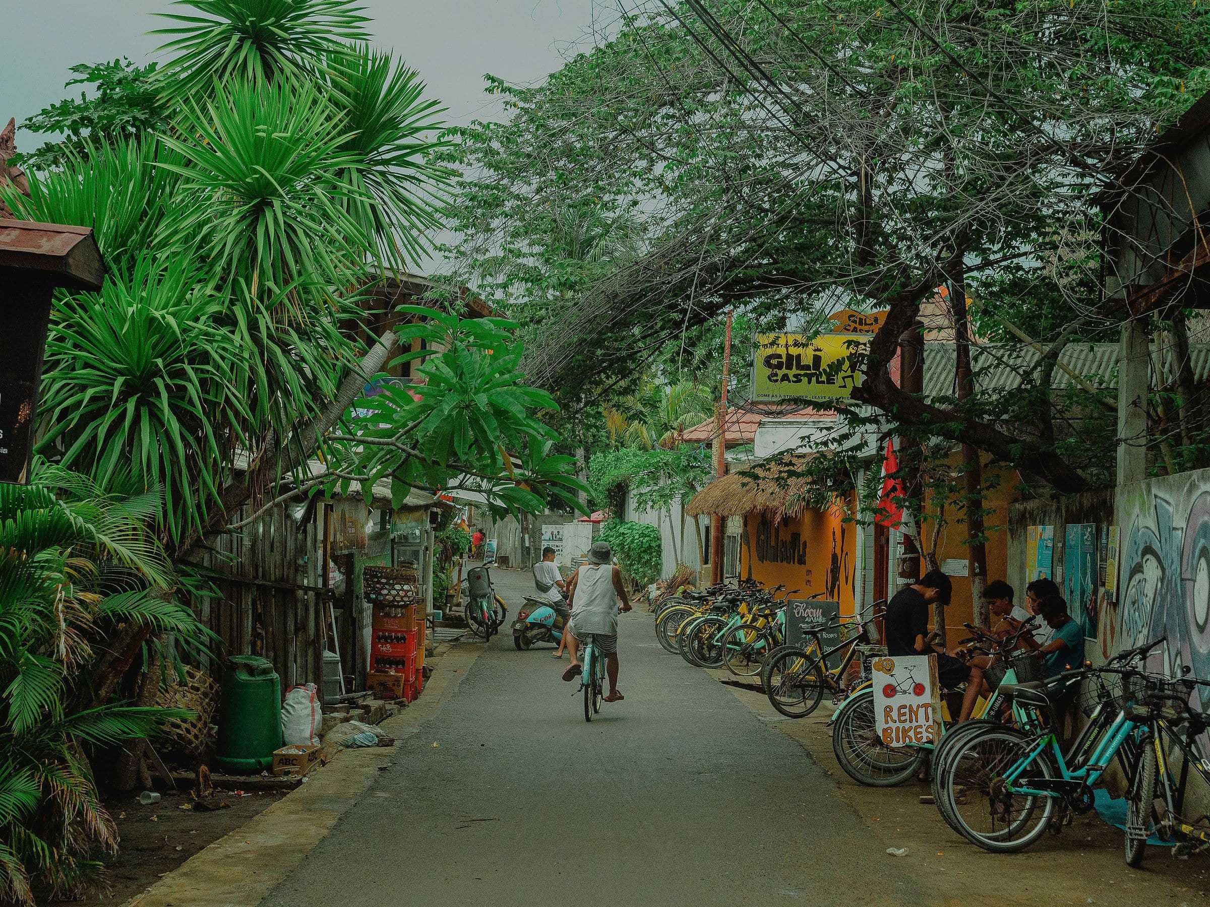 Een dorpsstraat op Gili Trawangan met fietsen, winkeltjes en palmen langs de kant