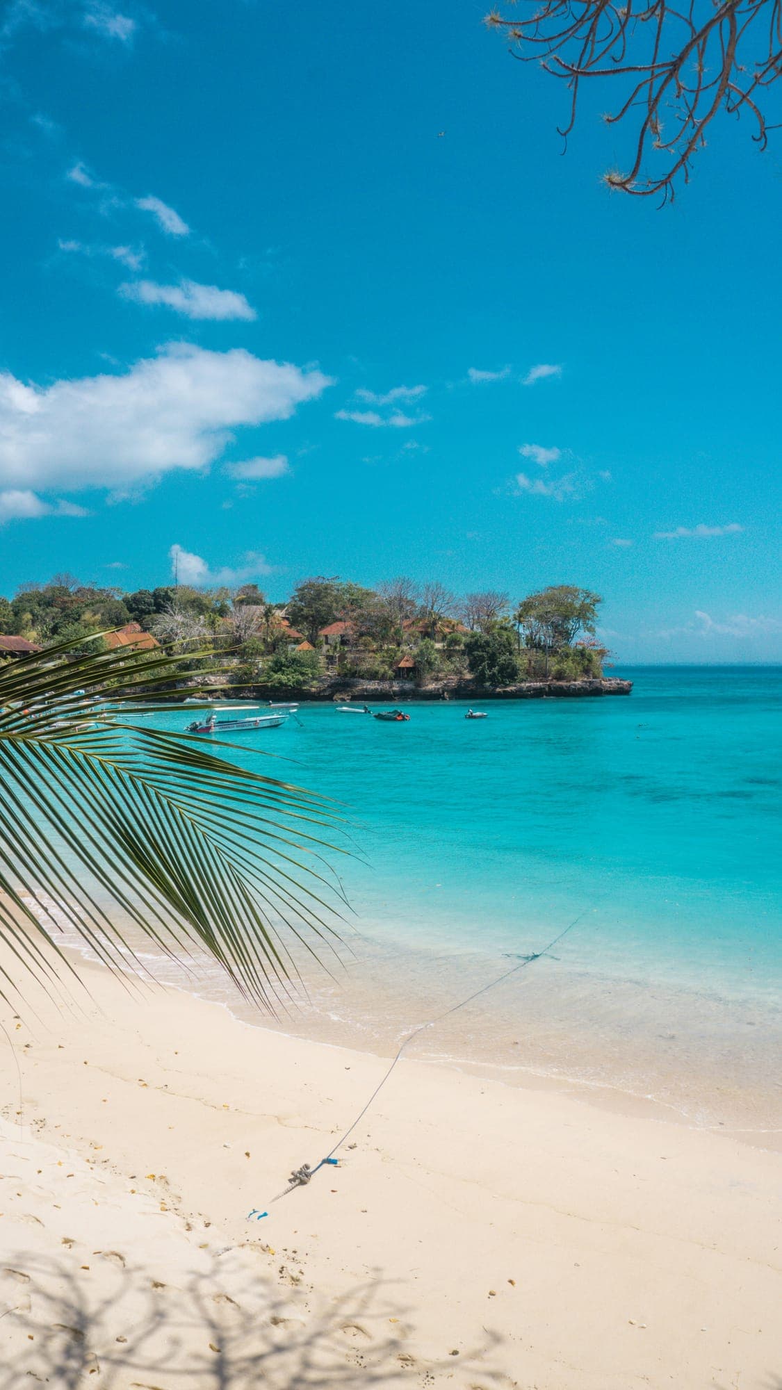 Turkooise baai met palmen en een rotsige landtong op Nusa Lembongan