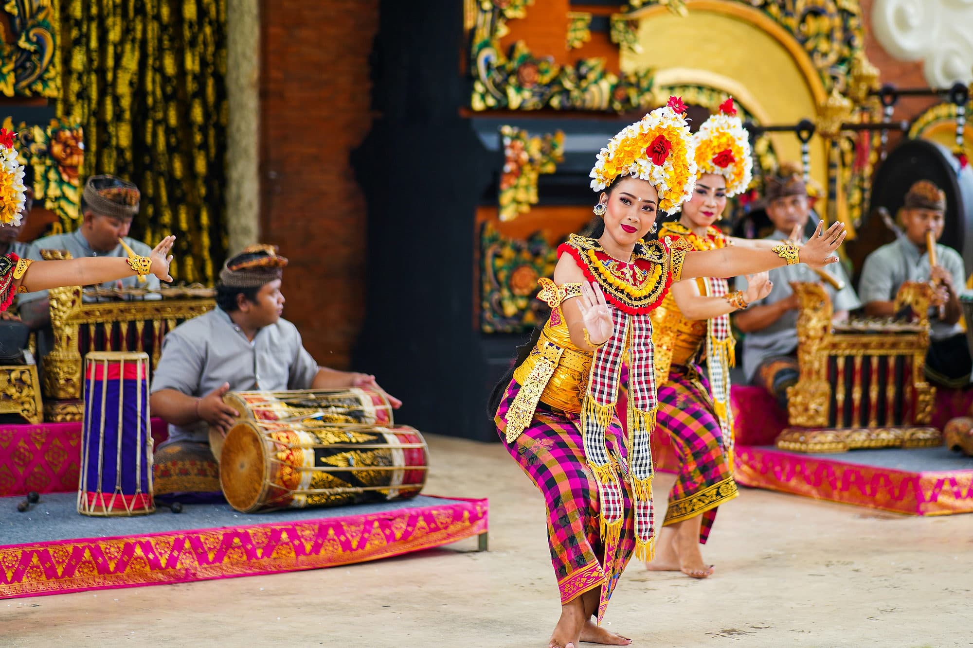 Balinese danseressen in gouden kostuum tijdens een Legong-voorstelling met gamelanspelers erachter
