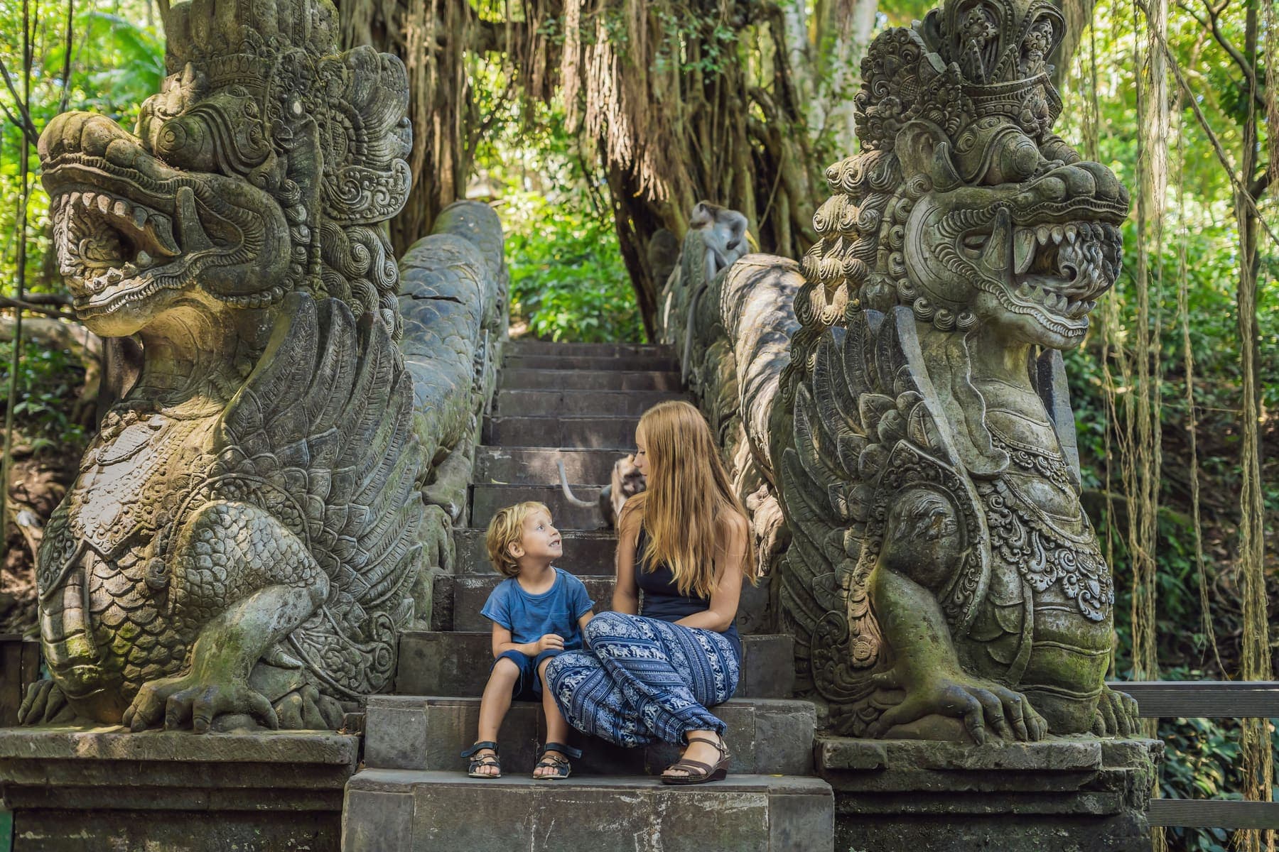 Mosbegroeide stenen trappen en beelden in het tempelbos van het Monkey Forest in Ubud