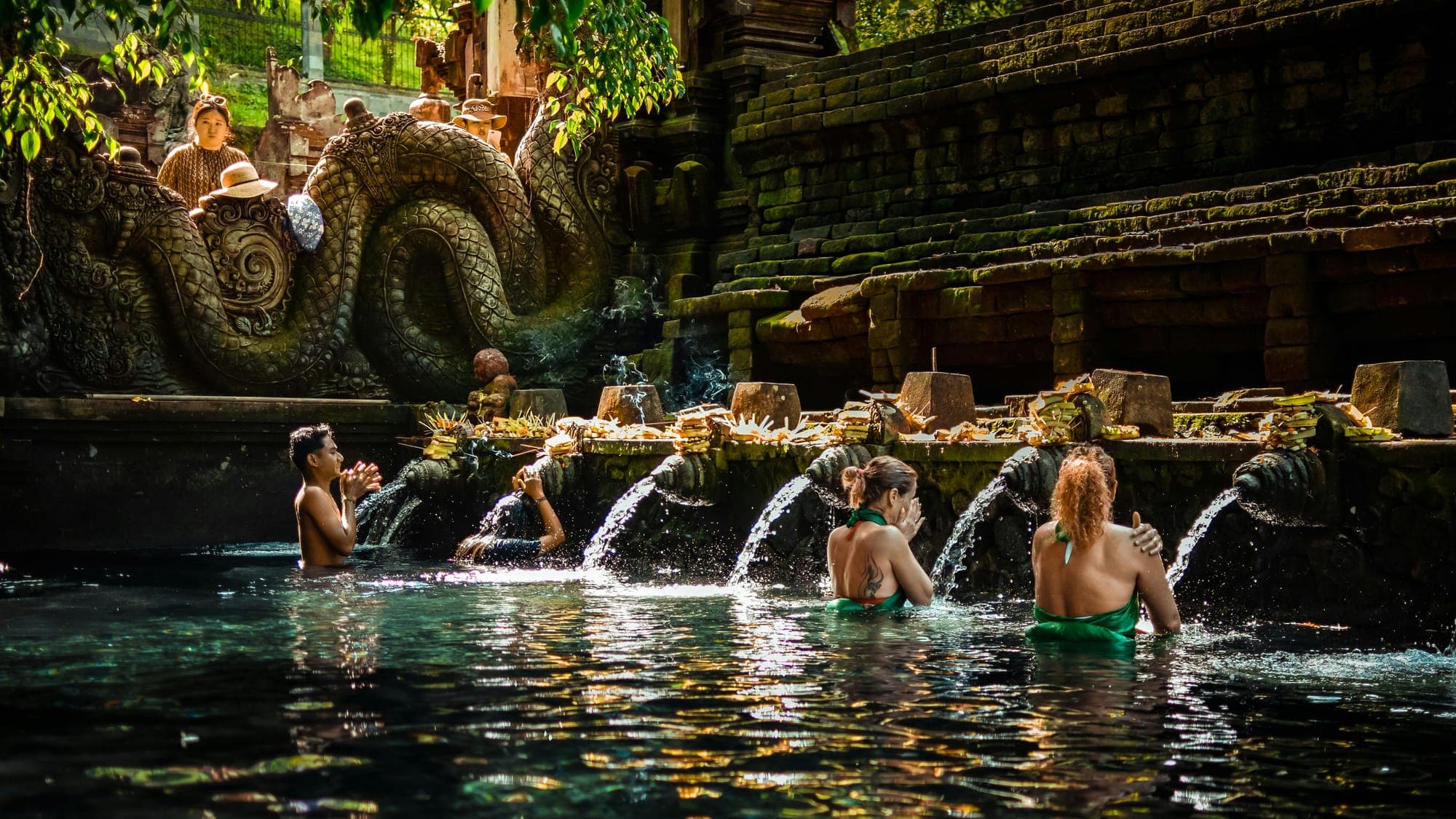 Bezoekers staan in het water onder de rij waterstralen van de heilige bronnen van Tirta Empul