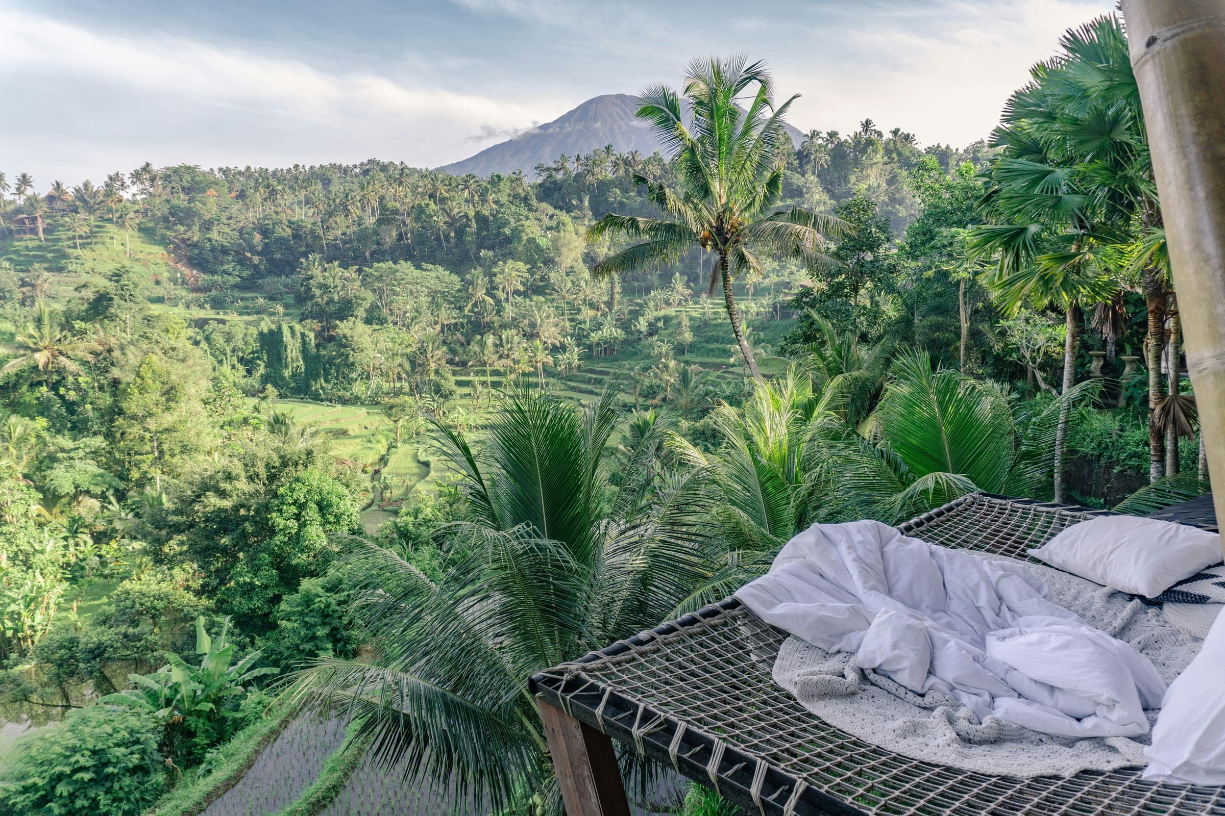 Uitzicht vanuit bed over de groene jungle en heuvels van Bali