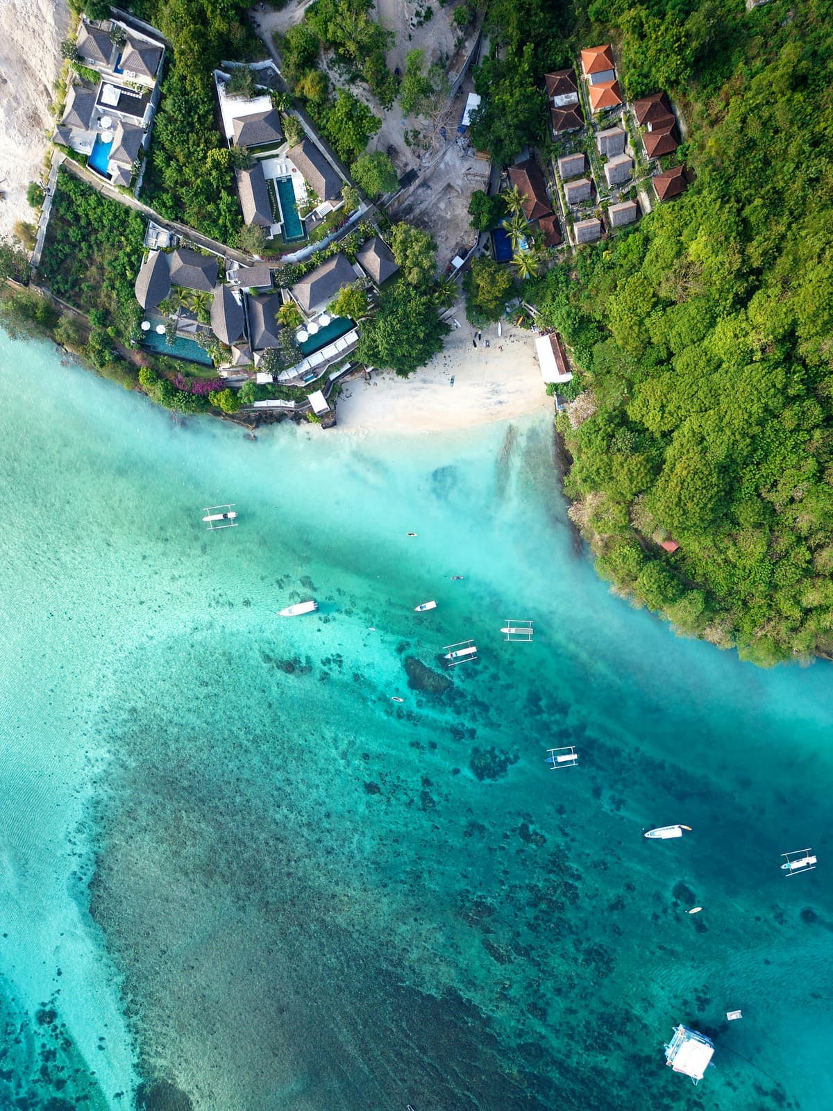 Turkoois water in een baai met wit zand en groene kliffen ernaast op Bali