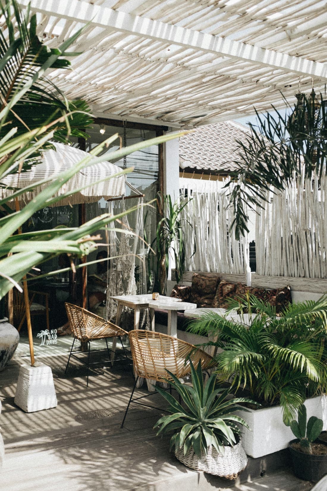 Terras van een café met rieten stoelen en planten in het zuiden van Bali