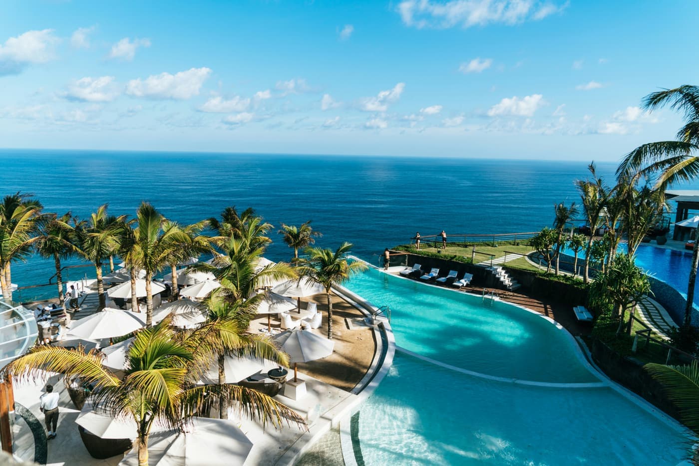 Infinity pool met parasols op een klif met uitzicht over de blauwe oceaan op Bali