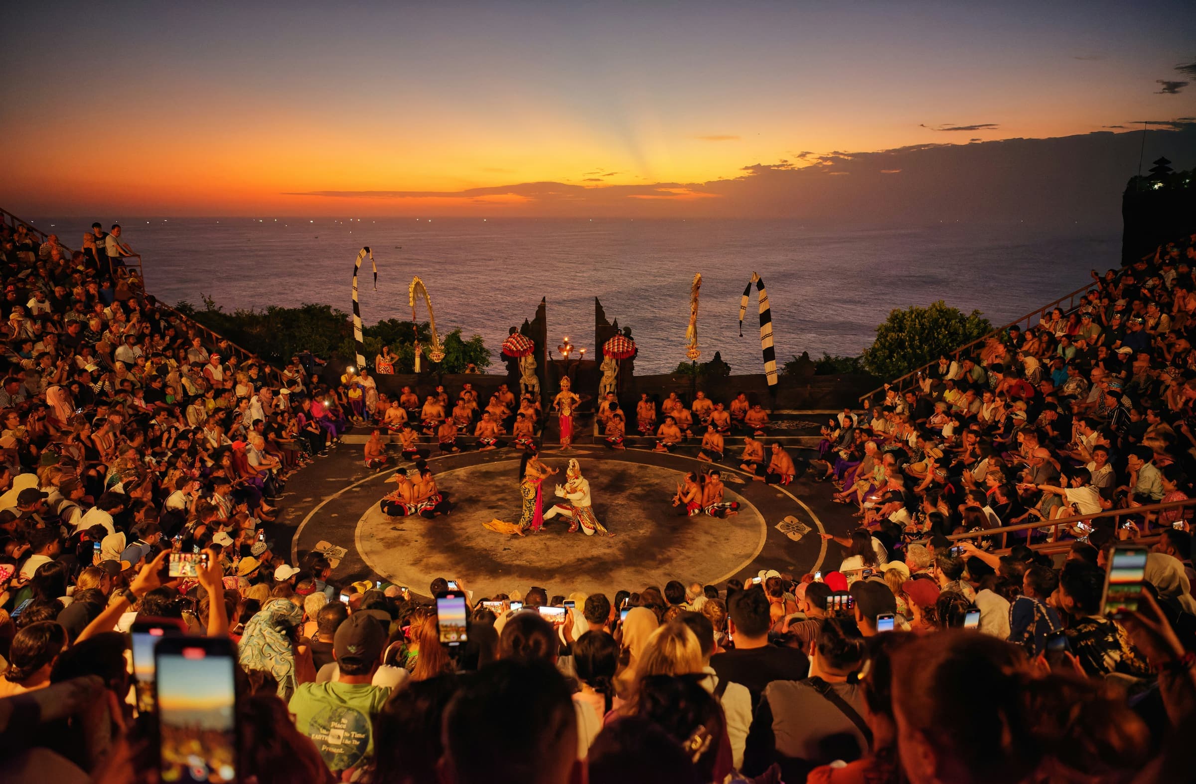 Het openluchttheater bij Uluwatu tijdens de Kecak-dans, met de oranje lucht boven de oceaan