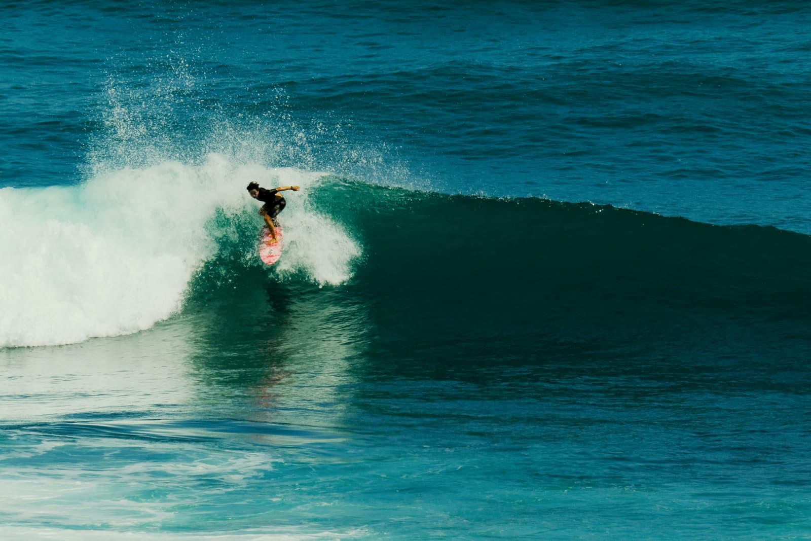 Een surfer rijdt door een turkooizen golf voor de kust van Bali