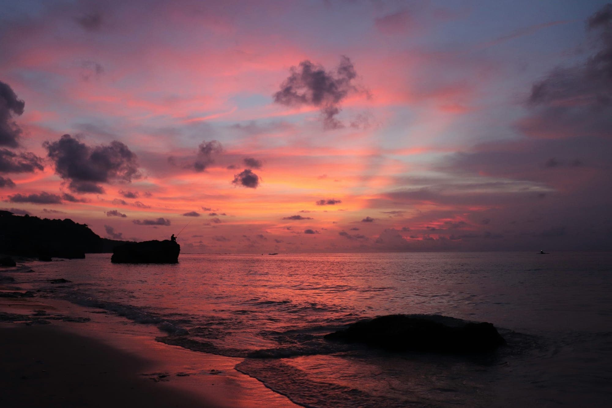 Roze en oranje lucht boven de zee tijdens de zonsondergang aan de kust van Uluwatu