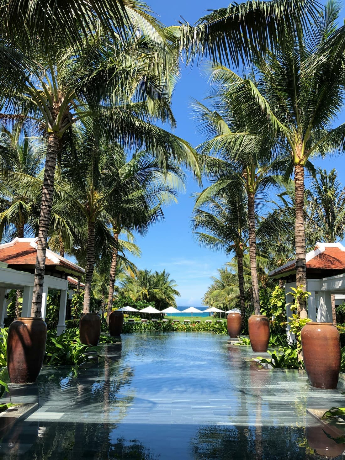 Zwembad tussen hoge palmen bij een resort aan de kust van Bali