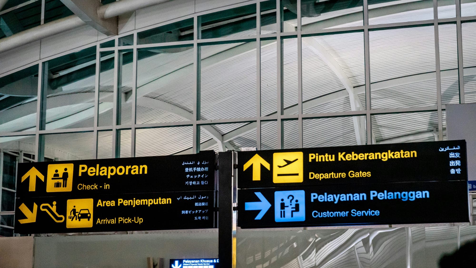 Wegwijzers op luchthaven Ngurah Rai met borden naar check-in, aankomst-pick-up en de vertrekgates