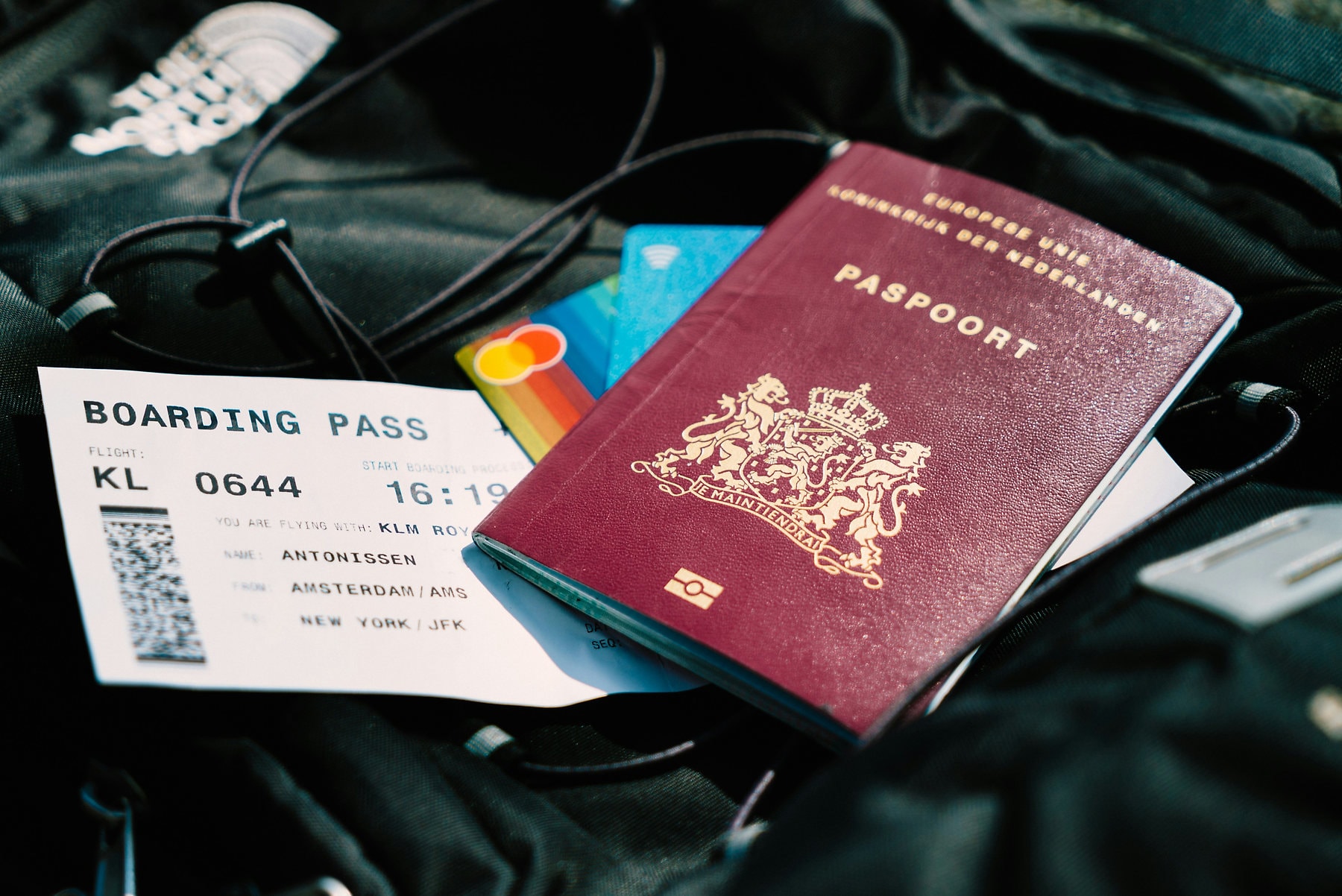 Een Nederlands paspoort met een boardingpass en een bankpas op een leren reistas