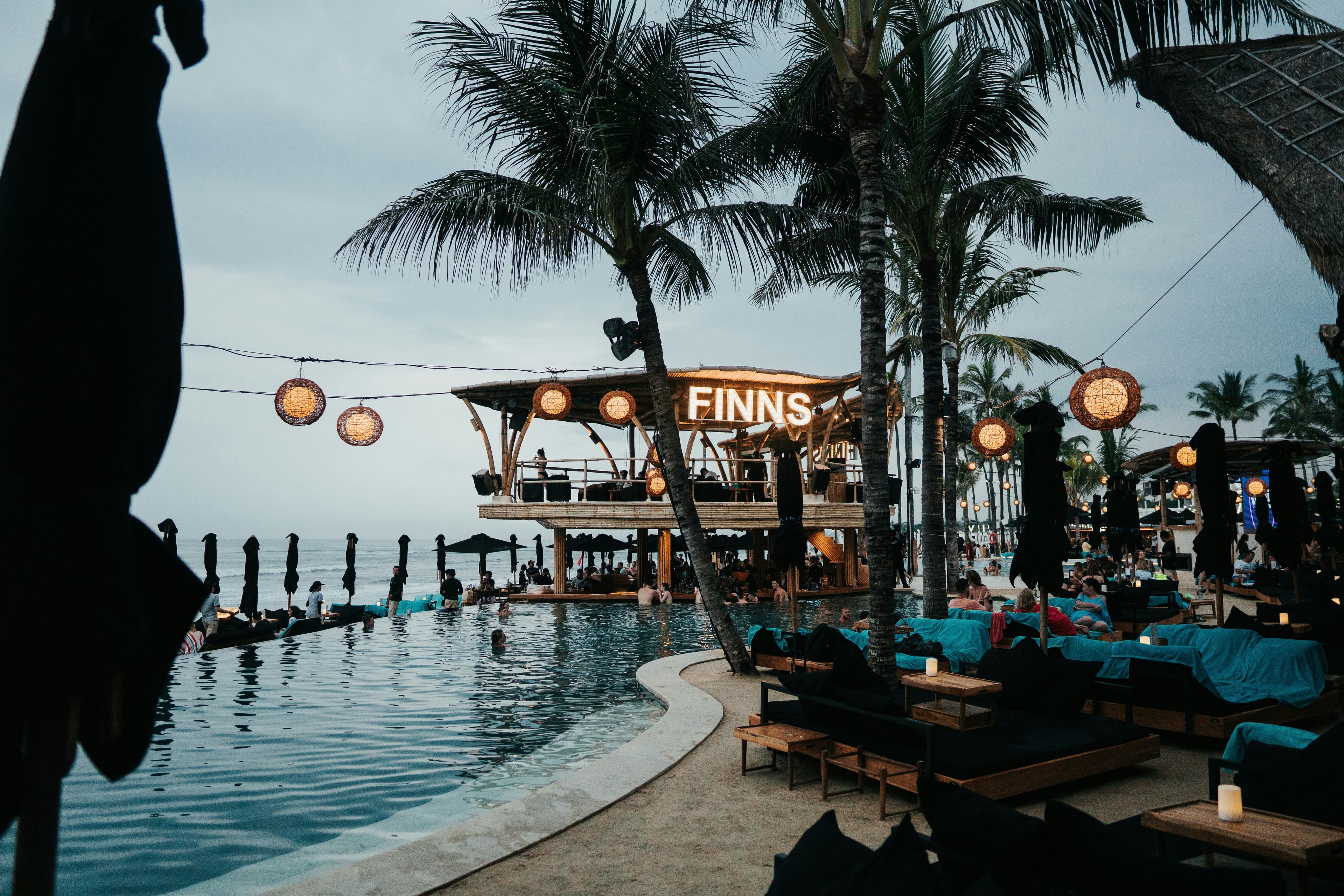 Palmen en surfers bij een beachclub aan het strand van Canggu op Bali