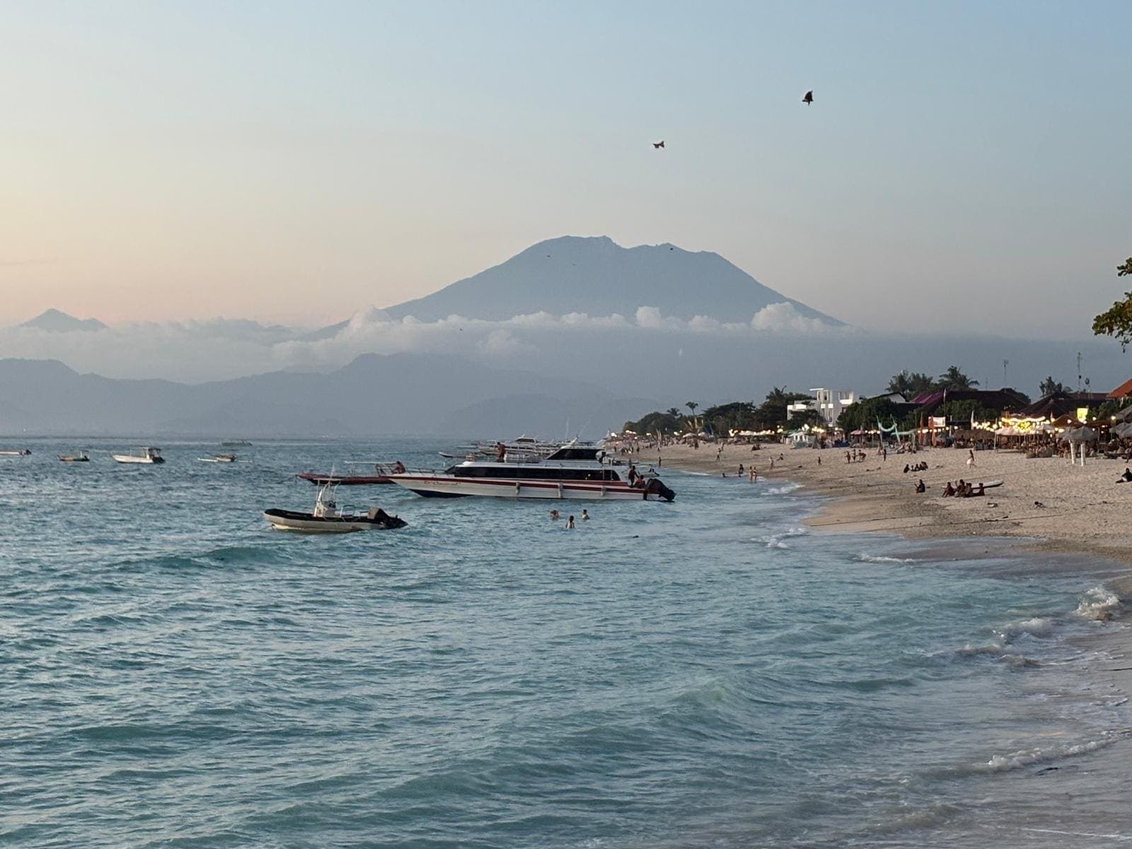 Het strand van Jungutbatu op Nusa Lembongan met bootjes voor de kust en de vulkaan Agung aan de overkant