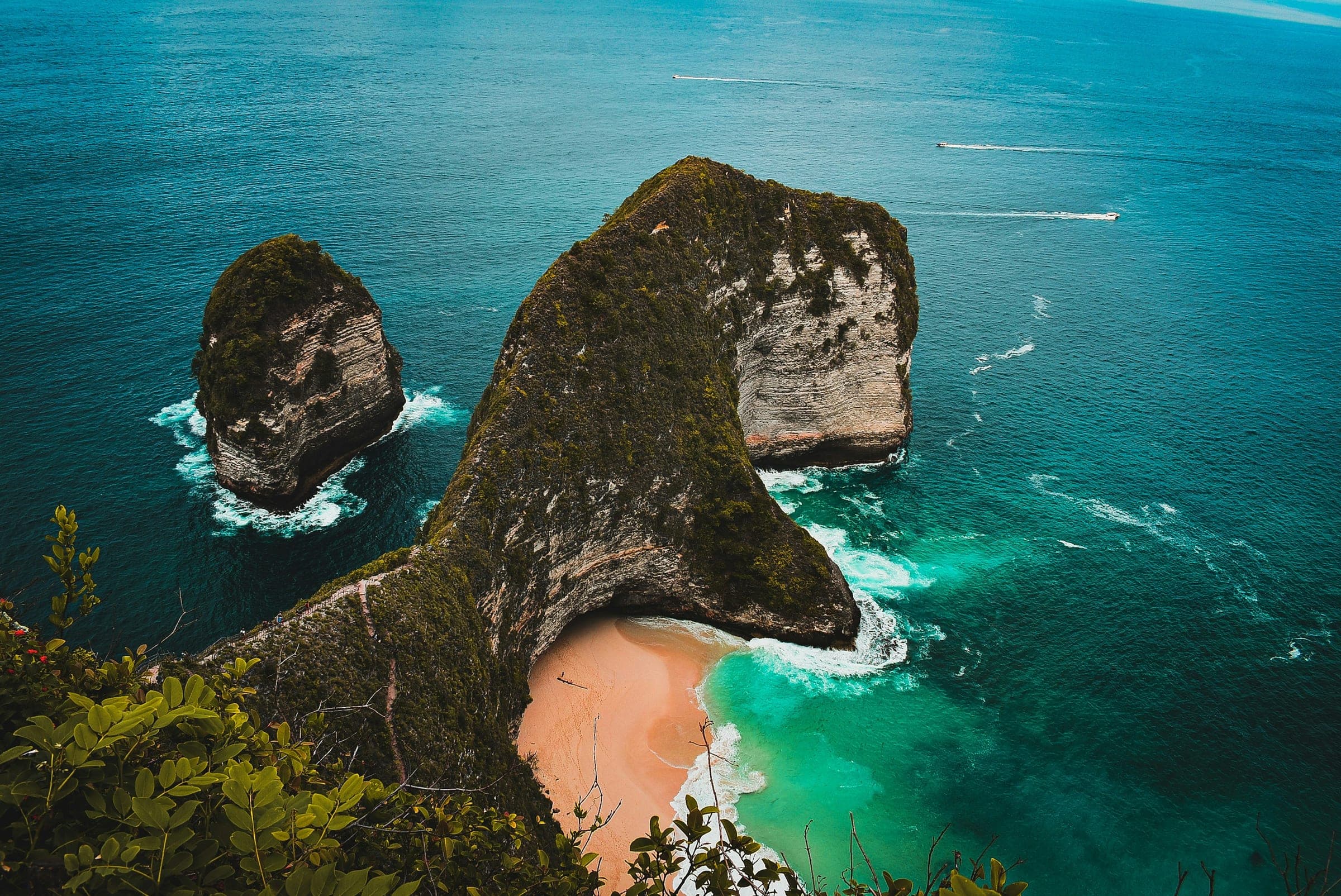 De kliffen van Kelingking Beach op Nusa Penida met turkoois water en een wit strand ver beneden