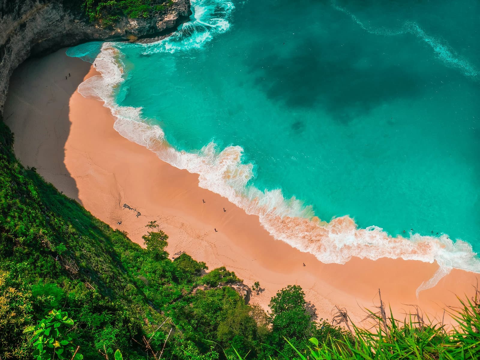Het strand onder de klif van Kelingking op Nusa Penida, met turkoois water en witte branding