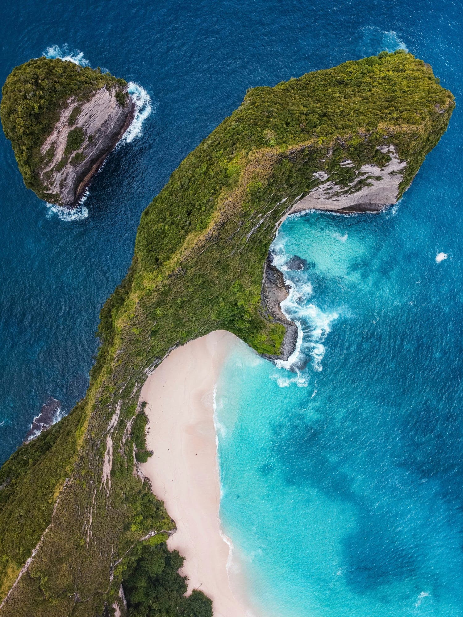 Verscholen baai met een klein strand tussen de groene kliffen van Nusa Penida
