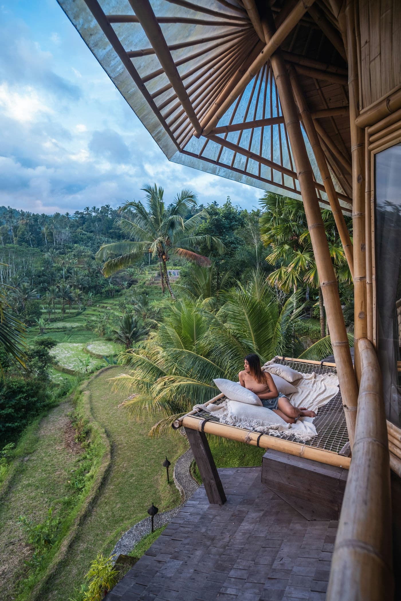 Een open bamboe villa met daybed en uitzicht over groene rijstvelden op Bali